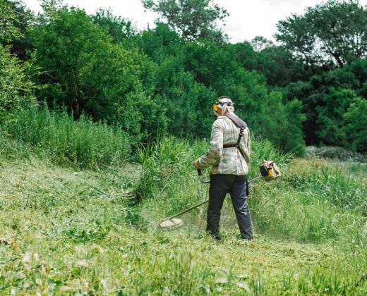 a-working-man-mowing-the-tall-grass-with-a-lawn-mower-